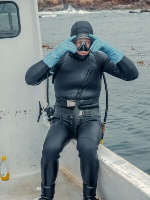 Man in Black Wet Suit and Black Helmet Riding on Black and White Boat